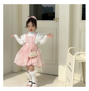 Detail of girls pink tulle tutu dress and pearl handbag with cream cafe backdrop