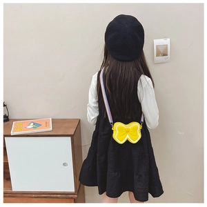 Detail view of yellow bow silicone mini bag with a colorful rainbow strap on a girl