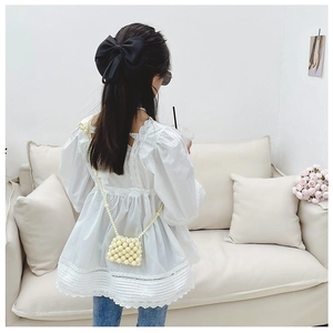 Dettaglio di una mini borsa fatta a mano con perle color crema e tracolla di perline
