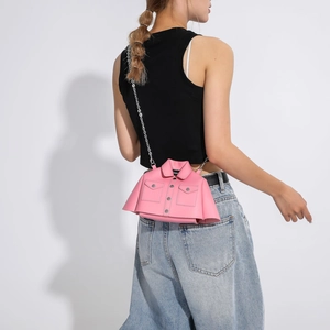 Pink jacket-shaped creative crossbody bag with silver chain strap shown on a model