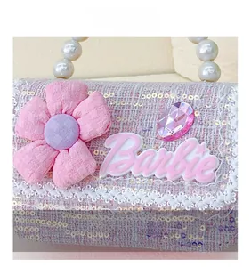 Detail of pink tweed texture, fabric flower, and pearl handle on girls small handbag