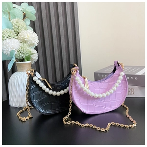 Close-up of crocodile pattern bags with pearl handles and golden chain straps