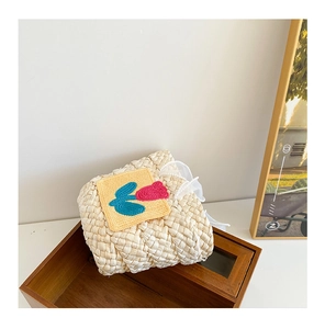 Detail of woven straw handbag for girls with yellow tulip knit patch and lace drawstring