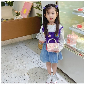 Sac bandoulière en tweed rose pour enfant avec poignée en perle porté par une fillette