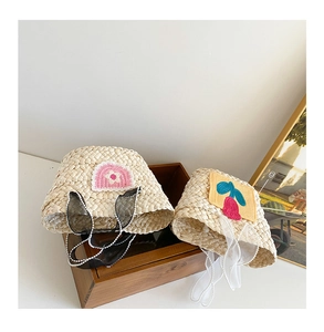 Detailed view of handmade straw hats with floral and cherry crochet patches on a wooden box