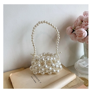 Close-up of handmade cream pearl woven handbag with detailed beadwork on vintage book