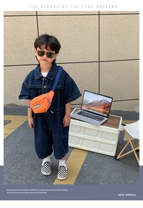 Détail d'un enfant portant un sac banane en toile orange avec une combinaison en jean