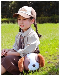 Detail of cute cartoon dog crossbody bag and baseball cap worn by a girl on the grass