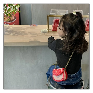 Détail d'un sac à bandoulière cœur rouge et rose pour fille avec chaîne dorée