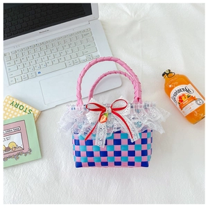 Detail of hand-woven pink and blue girls' checkered bag with lace trim and strawberry charm
