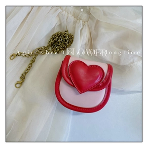 Détail du sac à bandoulière en forme de cœur rose et rouge avec chaîne dorée