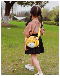Detailed back view of a cute yellow giraffe crossbody bag on a child in a park
