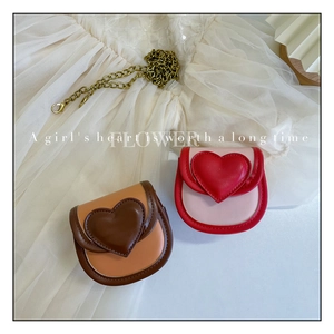 Détail de mini sacs à bandoulière en forme de cœur avec chaînes dorées sur dentelle