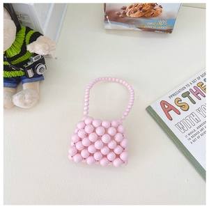 Dettaglio della mini borsa fatta a mano con perle rosa, manico elegante e texture intrecciata