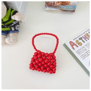 Dettaglio di una borsa a mano in perline rosse fatta a mano con manico rotondo