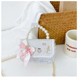 Détail du sac enfant en tweed bleu avec nœud, poignée en perles et bordure dentelle