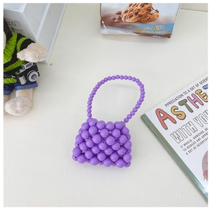 Dettaglio di una mini borsa fatta a mano con perle viola e una tracolla a catena