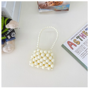 Dettaglio della mini borsa di perle color crema intrecciata a mano con perline lucide