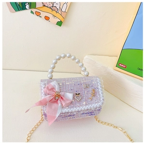 Détail d'un sac pour enfant en tweed rose avec poignée en perles et breloques mignonnes