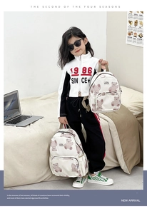 Detail of cute bear print canvas backpacks on bed showing two sizes for kids and parents