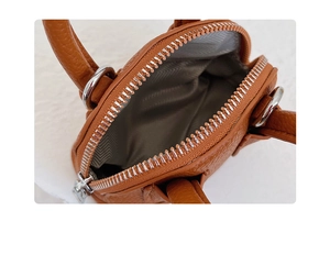 Close-up of brown pebbled leather shell bag showing silver zipper and herringbone lining