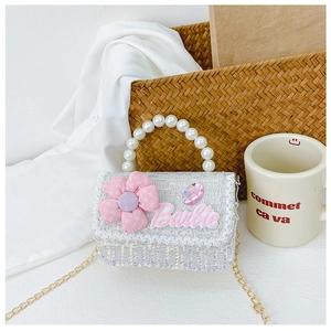 Detail of glitter mini crossbody bag with pink flower charm and pearl top handle