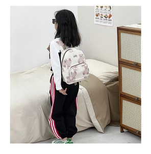 Detailed side view of a cute cartoon bear print backpack on a child model at home
