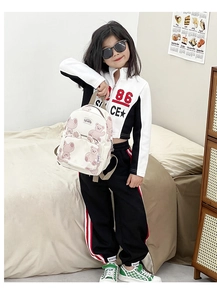 Detail view of a cute bear print cream backpack on a young girl in a cozy home setting