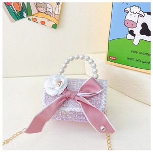 Detail of pink tweed kids handbag with pearl handle, ribbon bow and camellia flower
