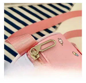 Detail of smooth golden zipper and cute cartoon prints on pink canvas cylinder bag