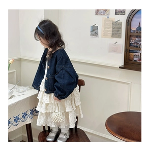 Dettaglio ragazza con giacca di jeans blu con gonna a balze crema e borsetta di perle