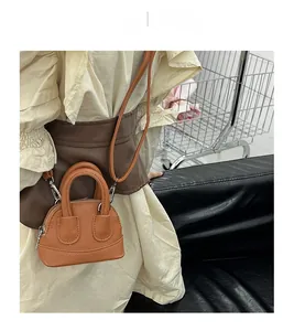 Close-up of orange-brown micro shell bag with lychee texture and thin crossbody strap