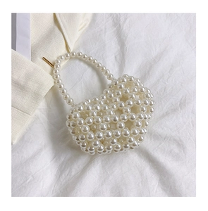 Dettaglio mini borsa a mano con perle bianche e manico intrecciato artigianale