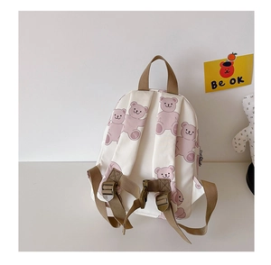 Close-up of pink bear print on cream canvas backpack with adjustable khaki straps