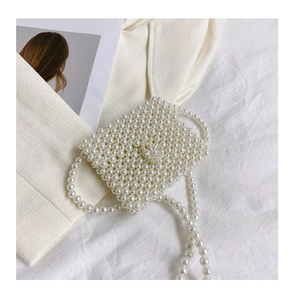 Dettaglio dell'elegante mini borsa a mano in perle bianche intrecciate su tessuto avorio