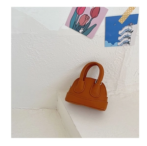 Detail of orange mini shell bag with lychee texture and metallic zipper for girls