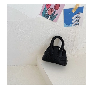 Close-up of black mini shell handbag with lychee pattern leather and top handles
