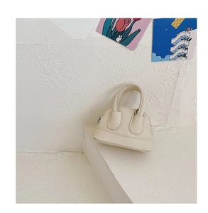 Detail of cream shell handbag with lychee pattern texture and metal zipper closure