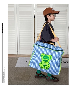Toddler girl wearing blue checkered bag with green bear print and yellow strap