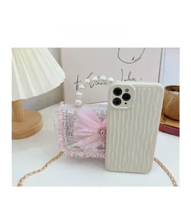 Mini pink tweed girls bag with pearl handle and bow next to a phone for size reference