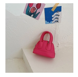 Detail shot of the lychee grain leather texture on a vibrant rose pink shell handbag