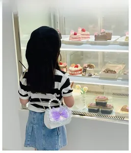 Girl standing with white sequin bag featuring purple mesh bow and pearl handle