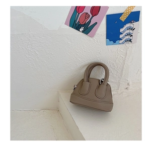 Close-up of a mini beige shell bag with litchi grain texture and curved handle details