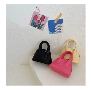 Close-up of mini leather shell bags in black, pink and yellow with metal zipper detail