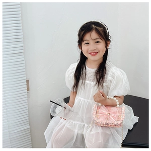 Close-up of pink woven toddler purse with mesh bow, pearl handle and gold chain