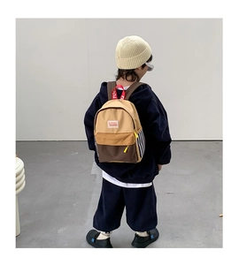 Detail of child wearing a color-block canvas backpack with striped side and red handle