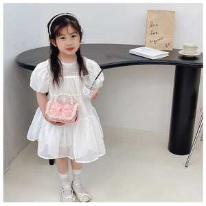 Detail of girls white puff sleeve princess dress with pearl accents and pink bow bag