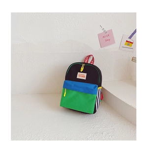 Detail of color-block canvas kids backpack with blue and green panels and a top red handle