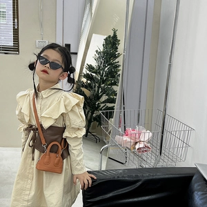 Girl shell handbag with beige ruffled dress and brown waist belt in a cozy studio setting