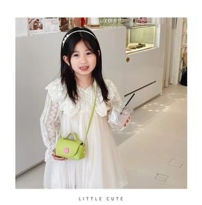 Detail of girl avocado green mini crossbody bag with pink button and long shoulder strap